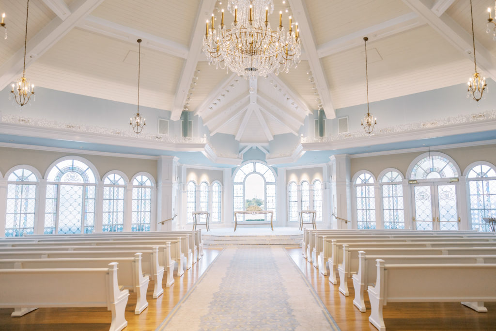Wedding pavilion with large golden and glass chandelier, with tall white ceiling and blue walls for Disney Film Wedding Photographer