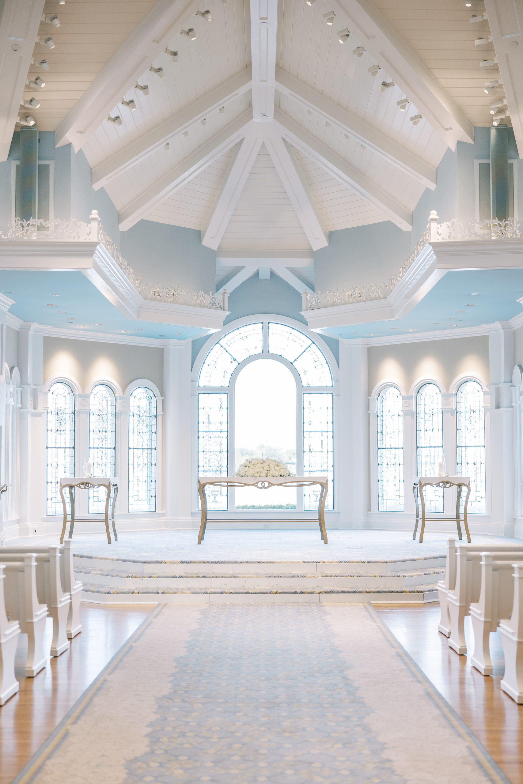 Inside of wedding pavilion that is white and baby blue, with altar and white pews for California Grill Wedding
