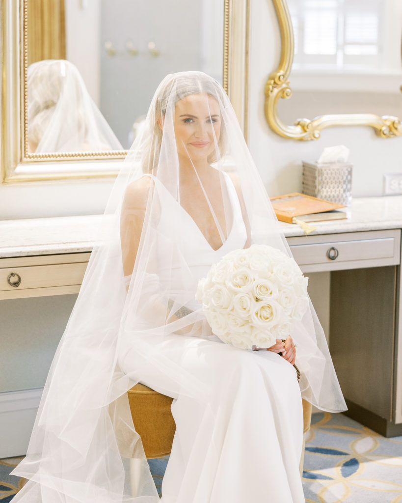 Bride sits with white rose bouquet with vail over head for Disney Film Wedding Photographer