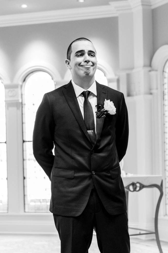 Groom waits and watches bride walk down the aisle, starting to cry for Disney Film Wedding Photographer