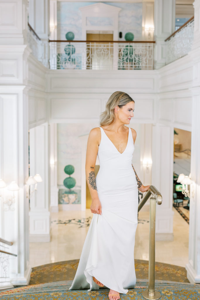 Bride walks up grand staircase and holds dress 