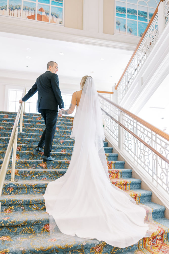 Groom leads bride up grand staircase for California Grill Wedding