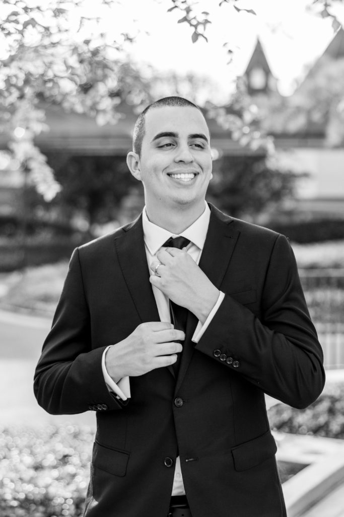 Groom smiles and adjusts tie in black and white for California Grill Wedding