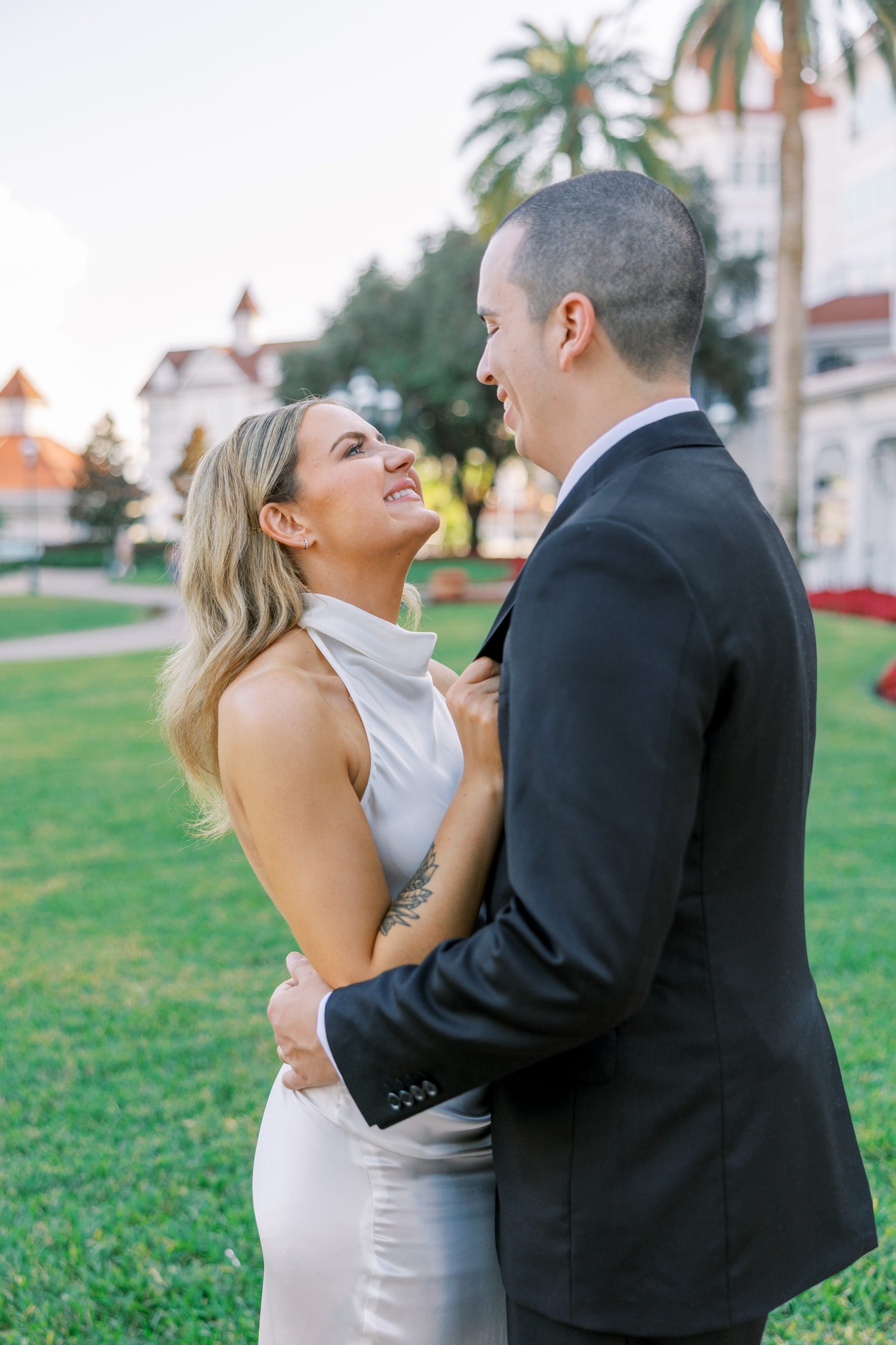Bride and groom embrace and smile into each other's eyes with green lawn and resort in background for California Grill Wedding