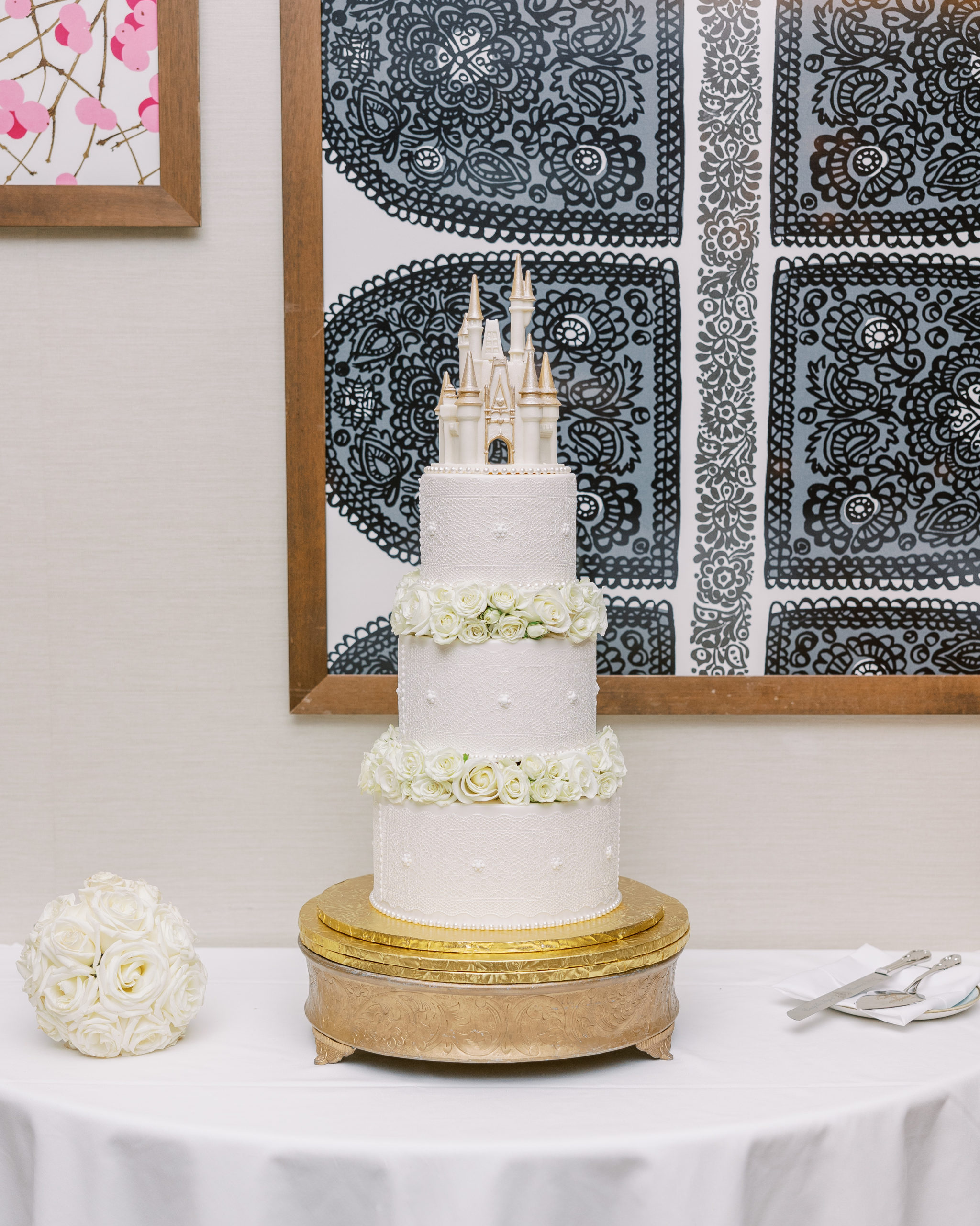 3-tier wedding cake with white roses and Disney castle at the top on golden platter for Disney Film Wedding Photographer