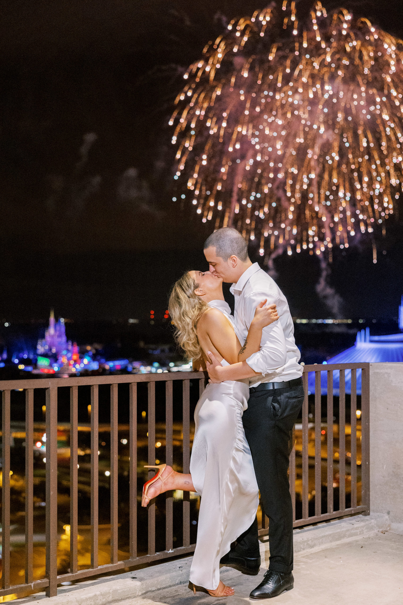 Bride and groom embrace and kiss outside with golden fireworks in the sky for California Grill Wedding 