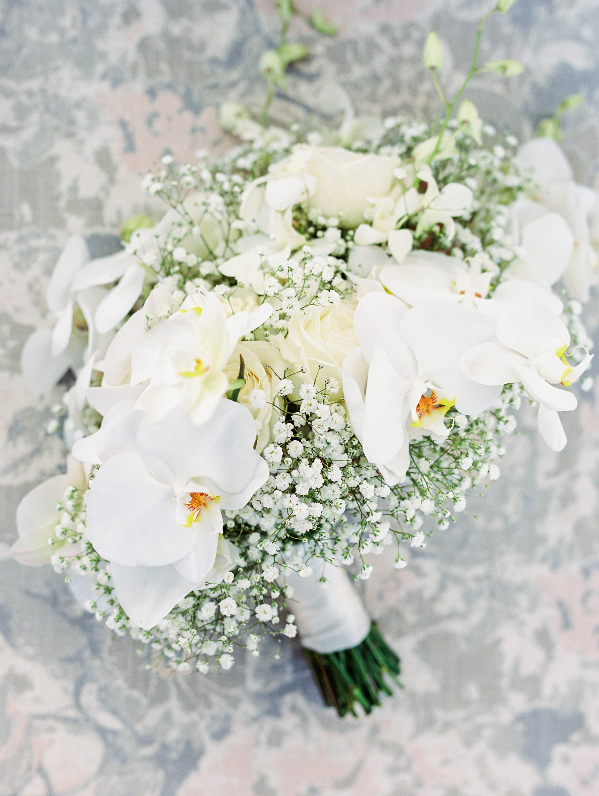 Up close view of bride's bouquet with ivory roses, baby's breath, and various white flowers Luxmore Grande Wedding