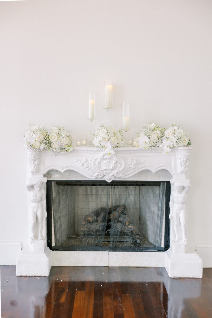 White detailed fireplace with white bouquets and candles for Luxmore Grande Wedding