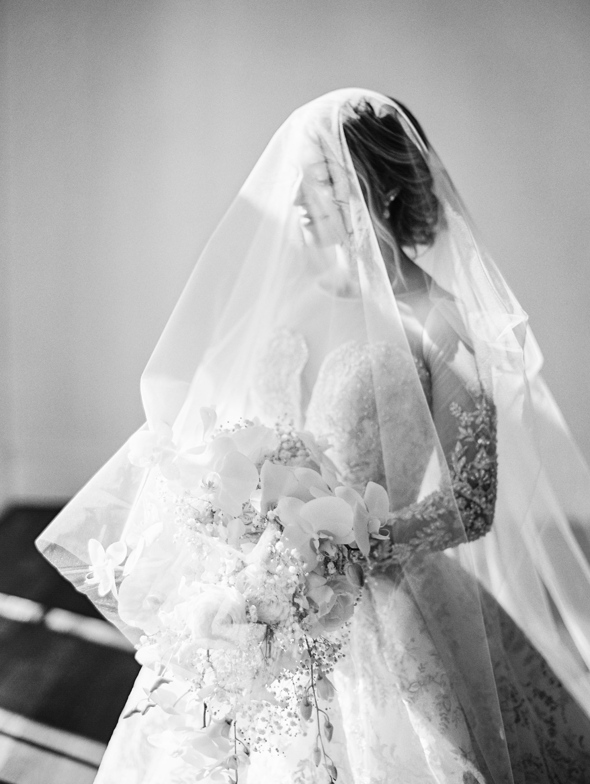 Bride wears veil over face and looks away posing holding bouquet for Luxmore Grande Wedding