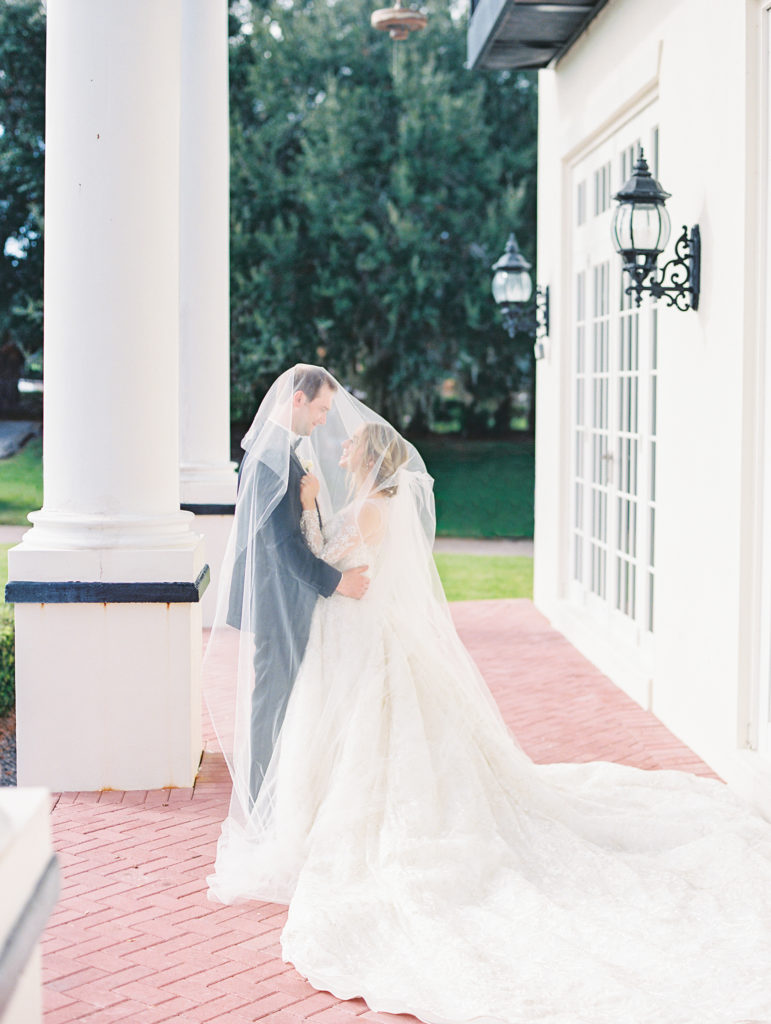 Bride and groom embrace underneath bride's veil 