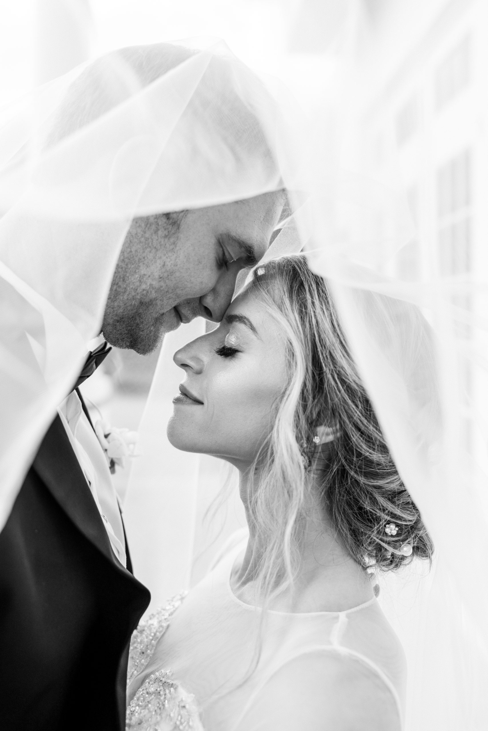 Bride and groom close eyes and rest under neath bride's veil in black and white for Luxmore Grande Wedding 