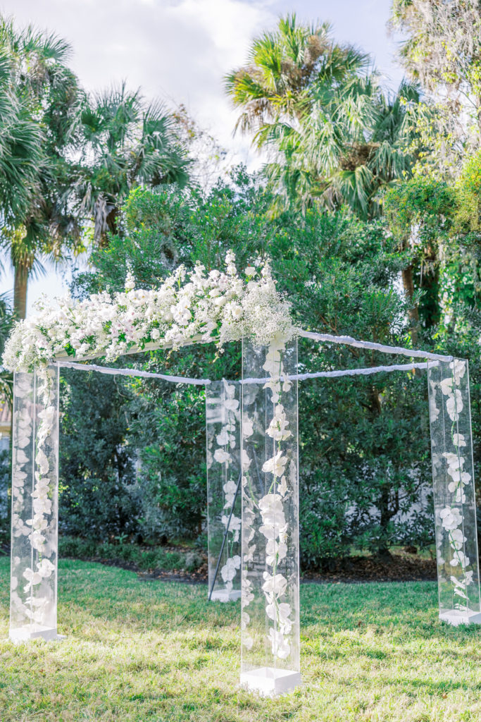 Delicate glass wedding arch with white flower arrangement 