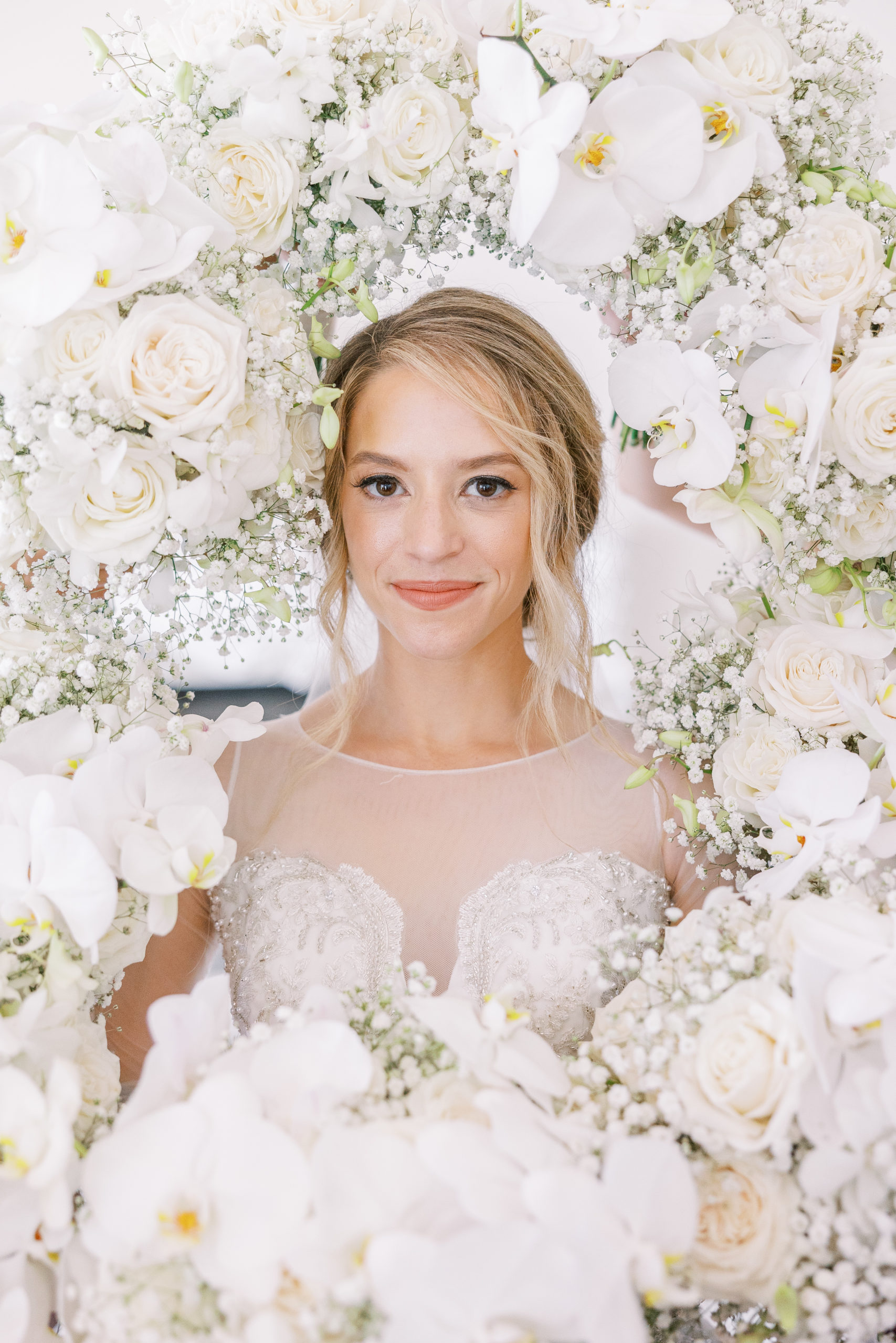 Bride poses with white rose flower bouquet and flower bouquets surround her head for Luxmore Grande Wedding