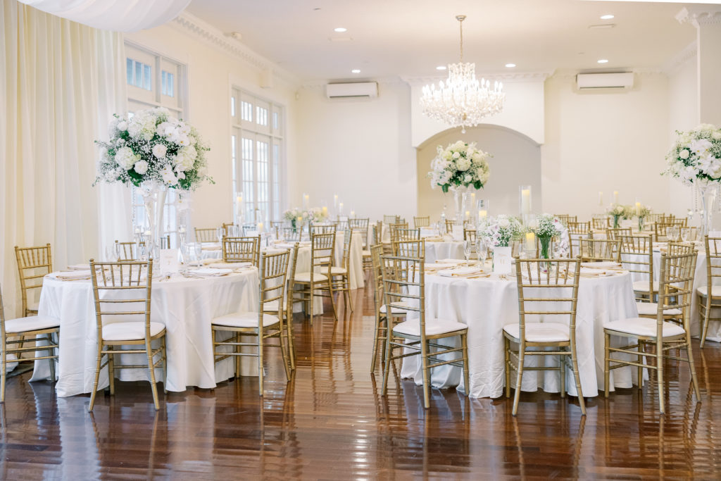 Wedding reception of round tables and tall white rose bouquet and chandelier for Luxmore Grande Wedding