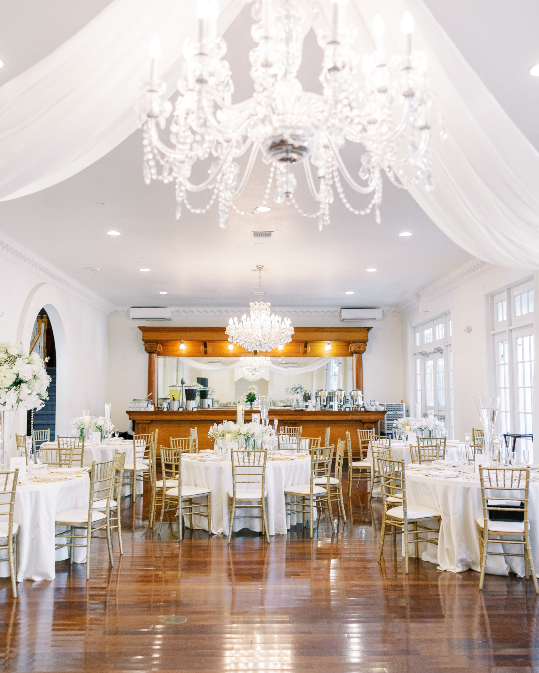 Wedding reception of round tables and white flower centerpieces with bar in back for Luxmore Grande Wedding