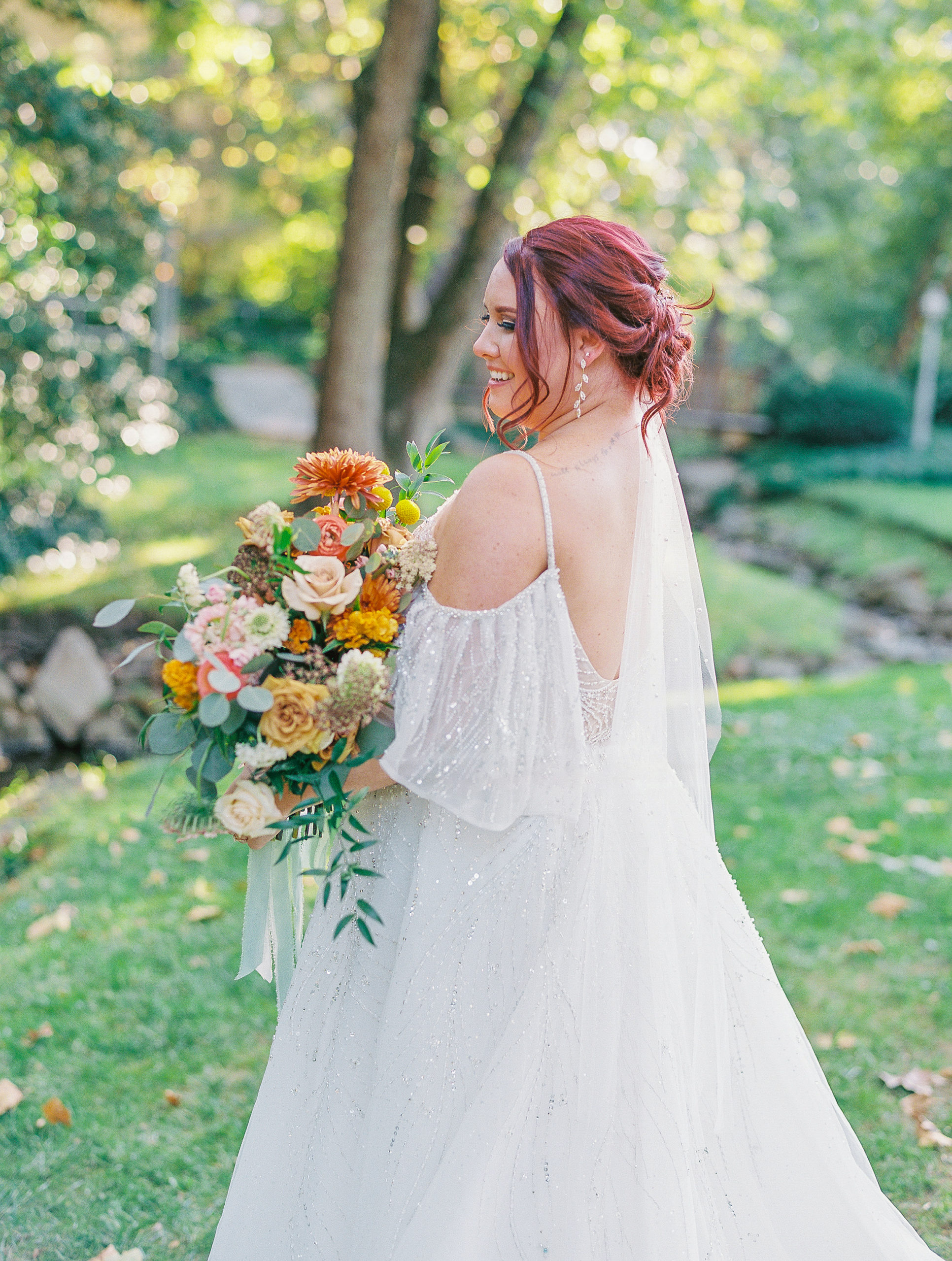 Bride faces away and smiles holding bouquet at this pomme radnor wedding