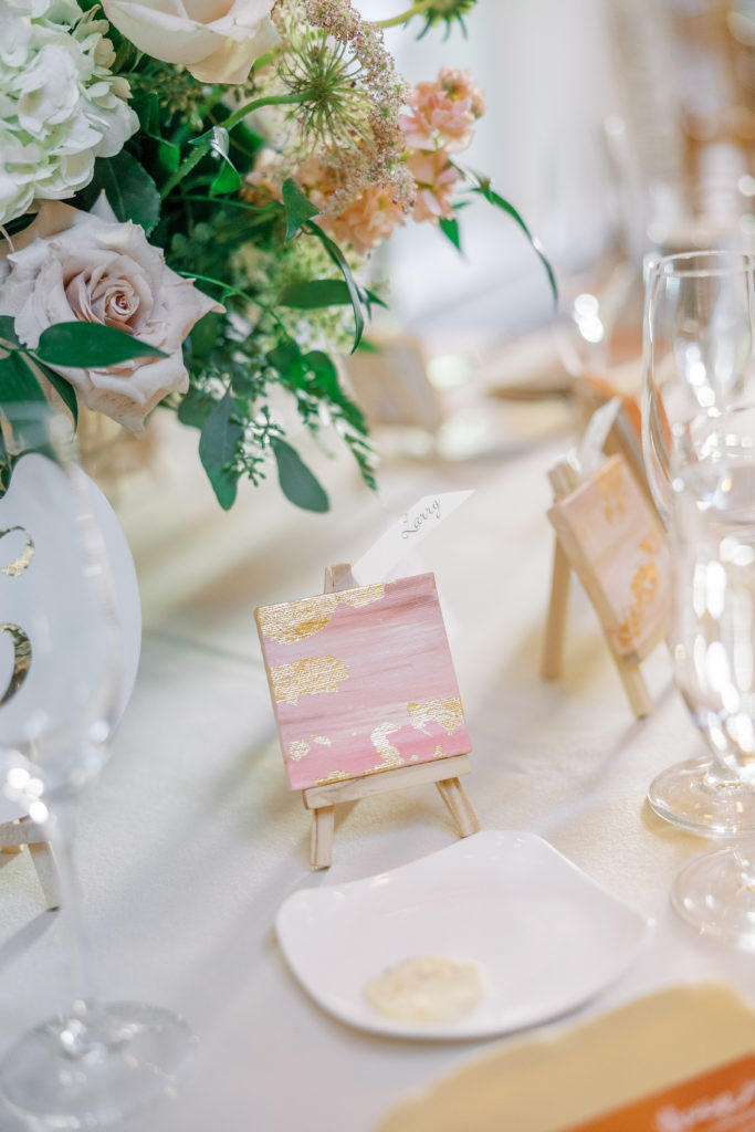 Reception name cards of small painting on easel and butter dish 