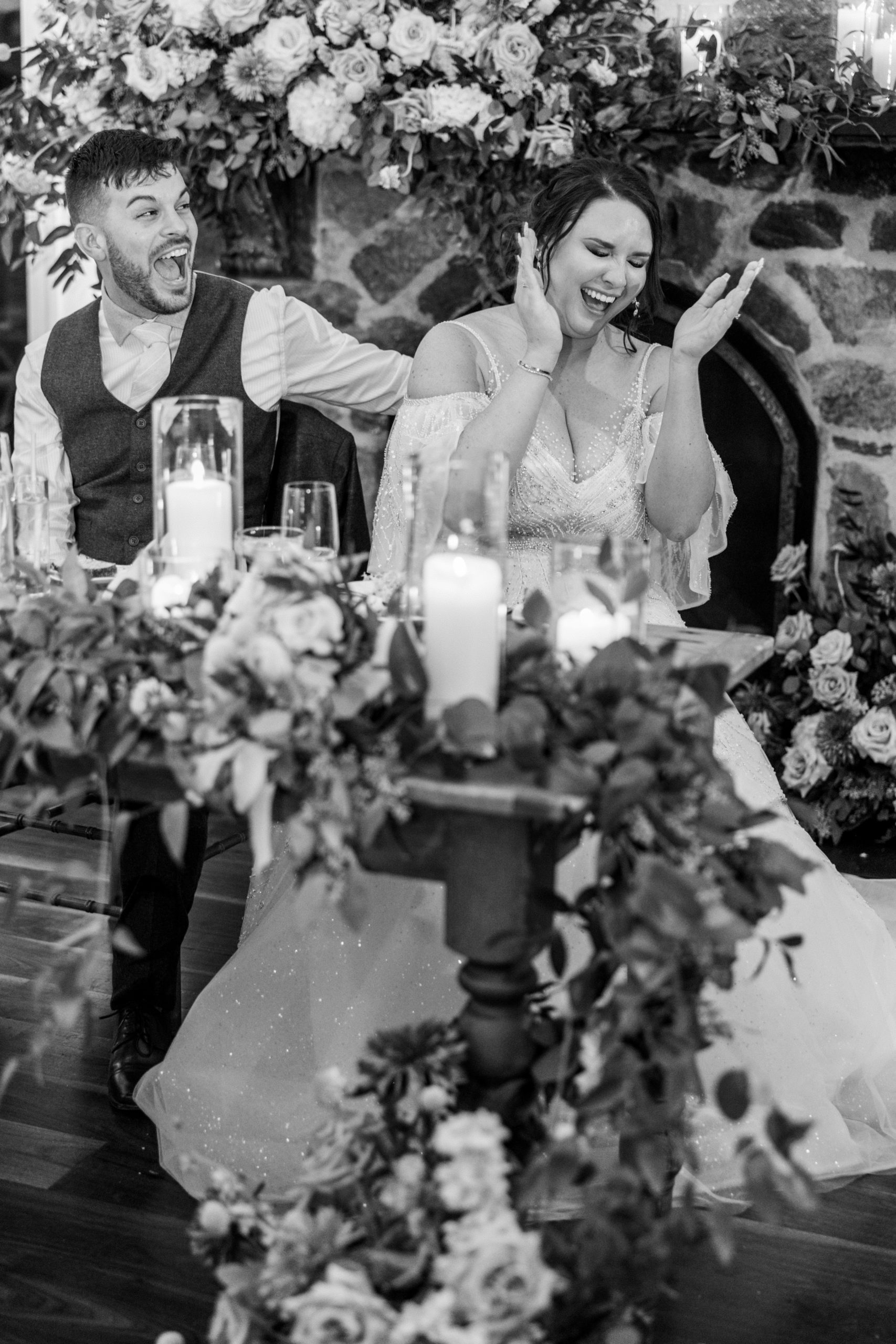 Bride and groom laugh during speeches sitting at their table at this pomme radnor wedding