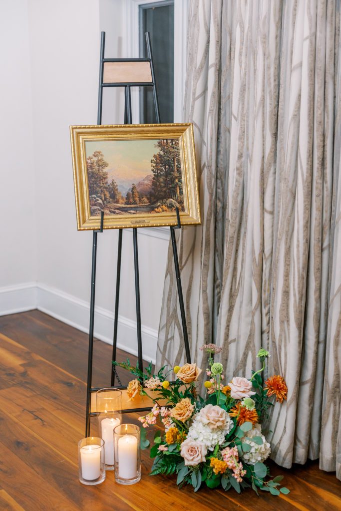 Flower arrangement and candles with painting on stand 