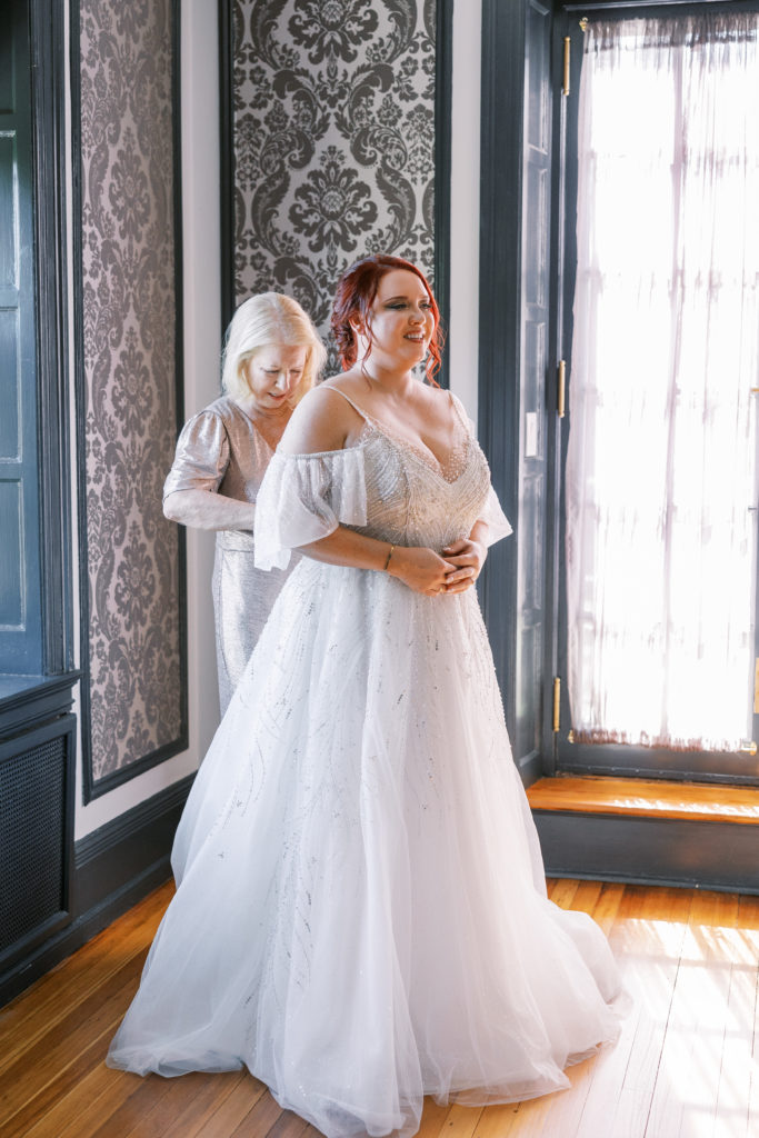 Bride gets help zipping up dress for philadelphia wedding photographer