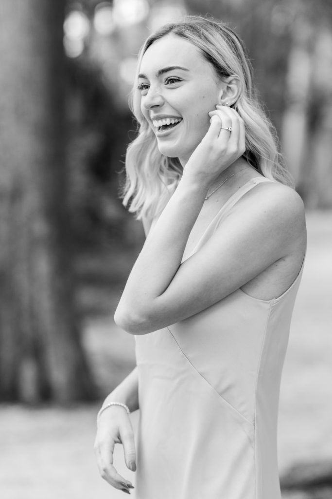 beautiful woman laughs while adjusting earring during engagement session