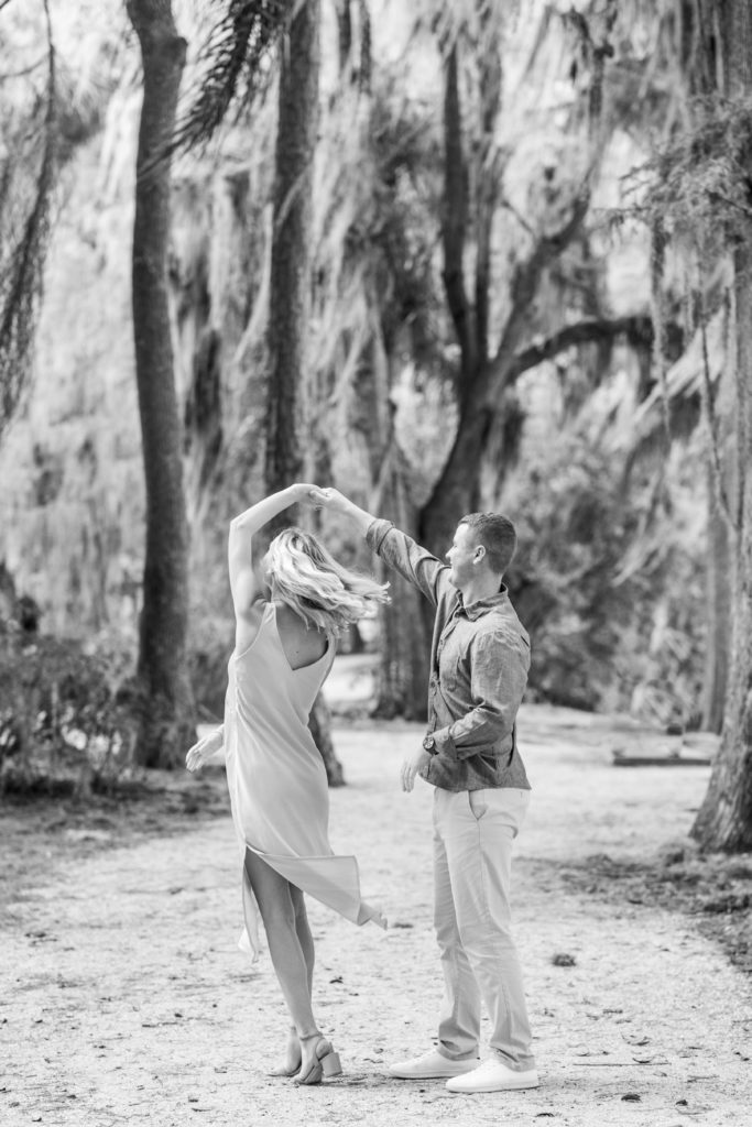 couple twirls in florida garden in black and white engagement photo