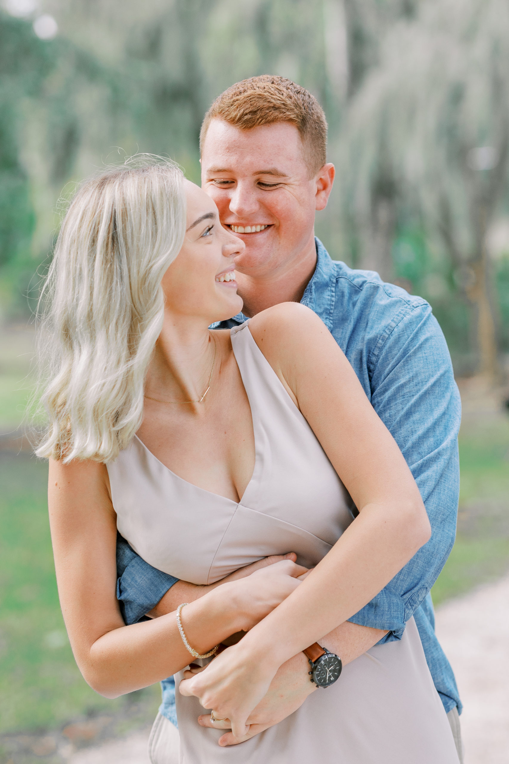 couple smiles joyfully with arms around each other in this Winter Park Engagement Session