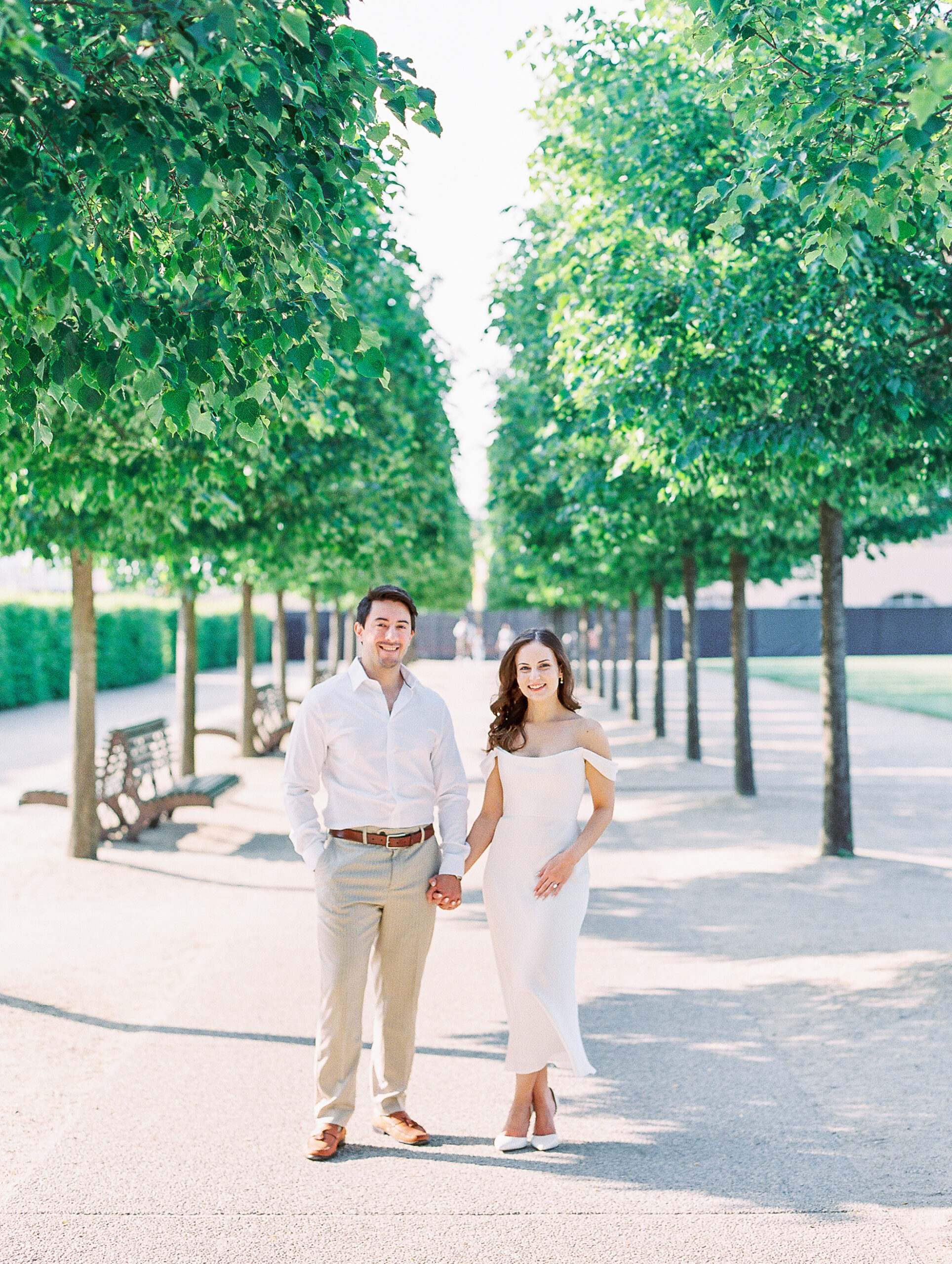 Spring Longwood Gardens Engagement Session shot on film by destination wedding photographer Katie Trauffer - couple stands hand in hand on tree lined path