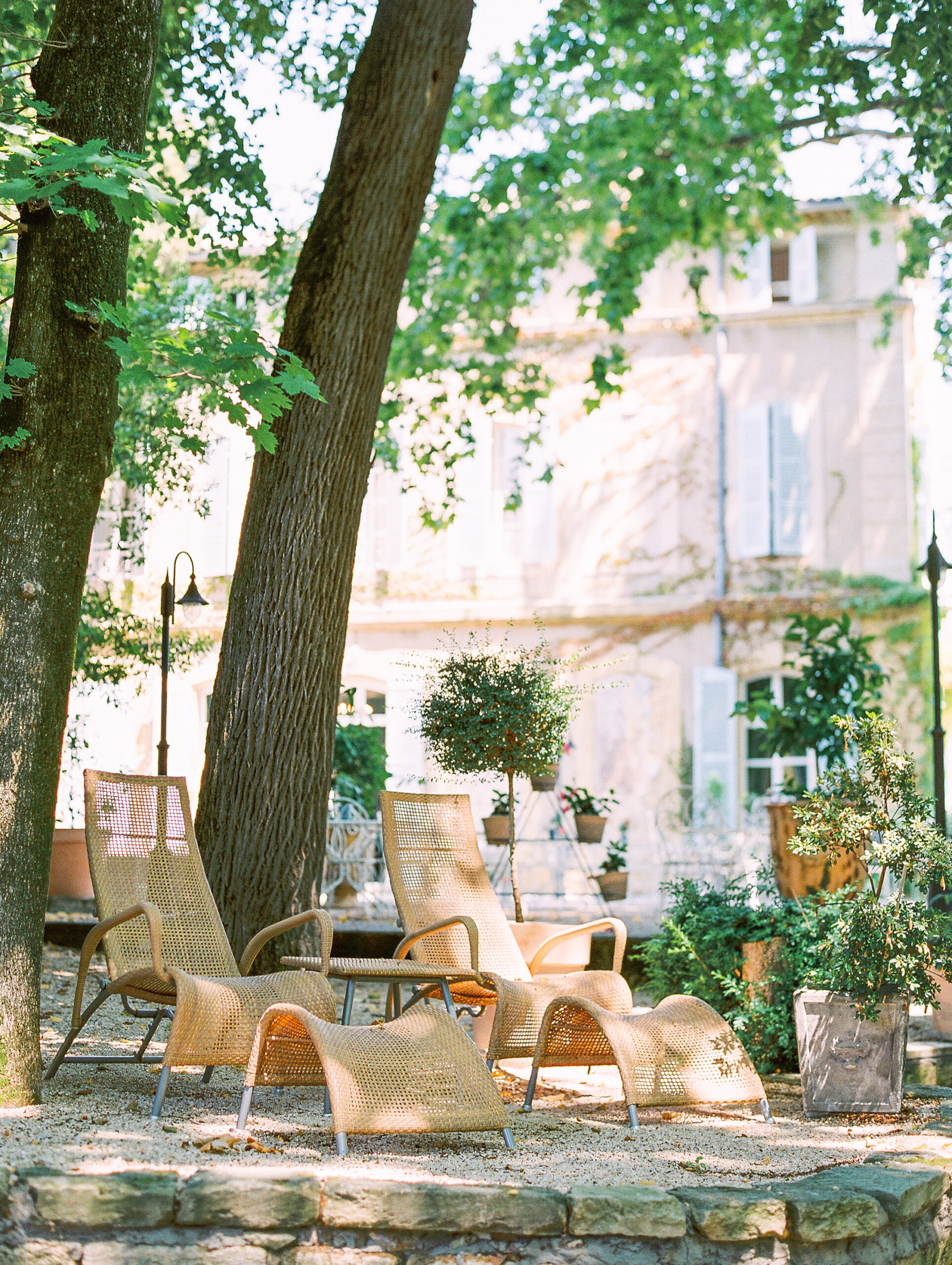 summer in provence louge chairs under dappled sunlight with large shady trees