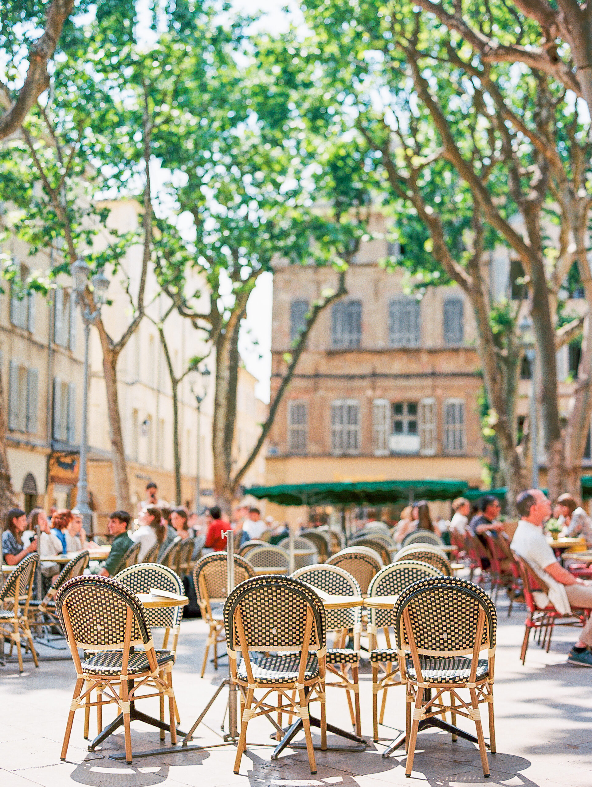 summer in provence sun soaked market square in aix-en-provence with rattan chairs and people lounging under shady trees