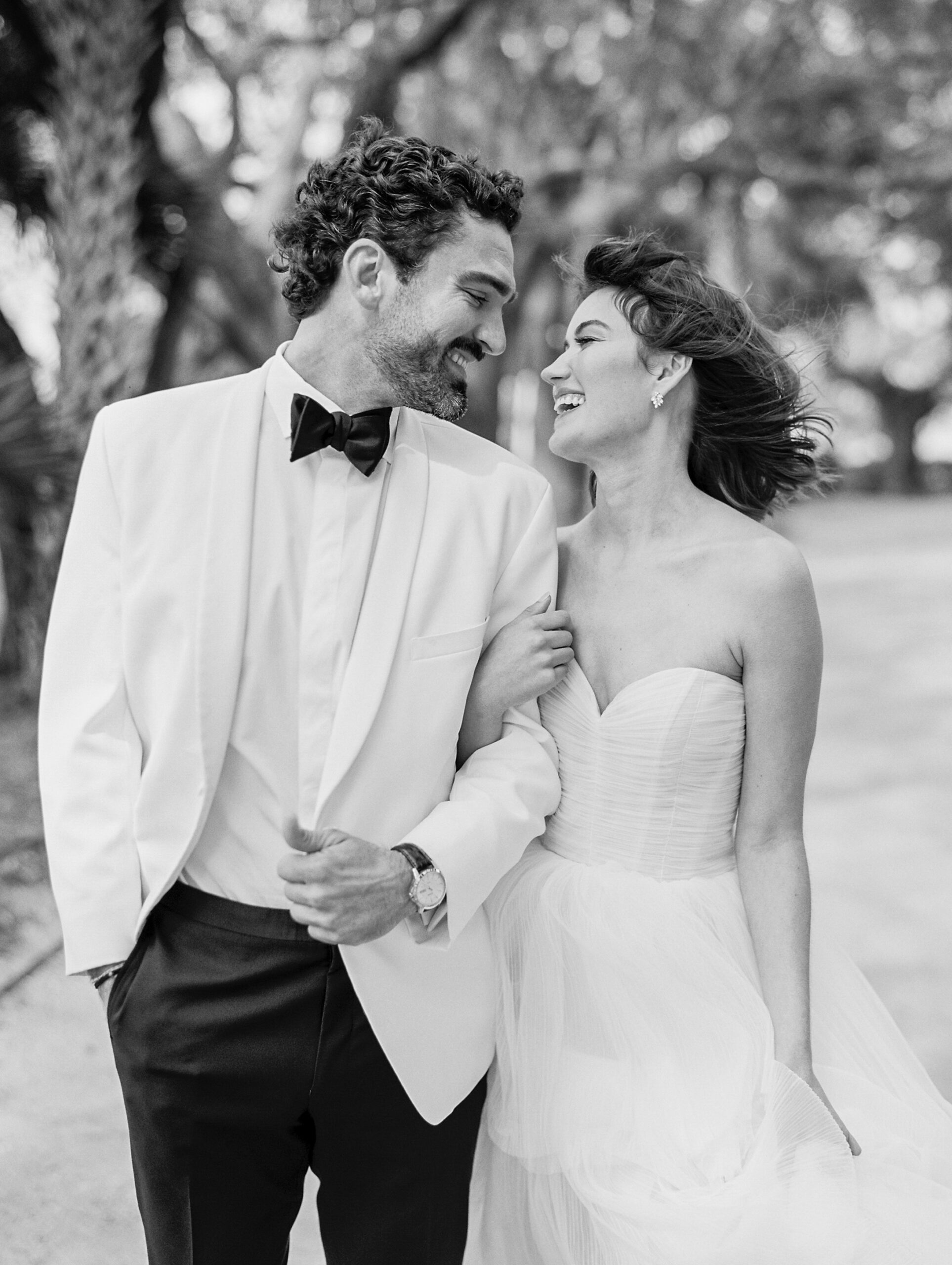 Lowdnes Grove Wedding by destination film wedding photographer Katie Trauffer Photography - bride and groom joyfully walk along palms in black and white