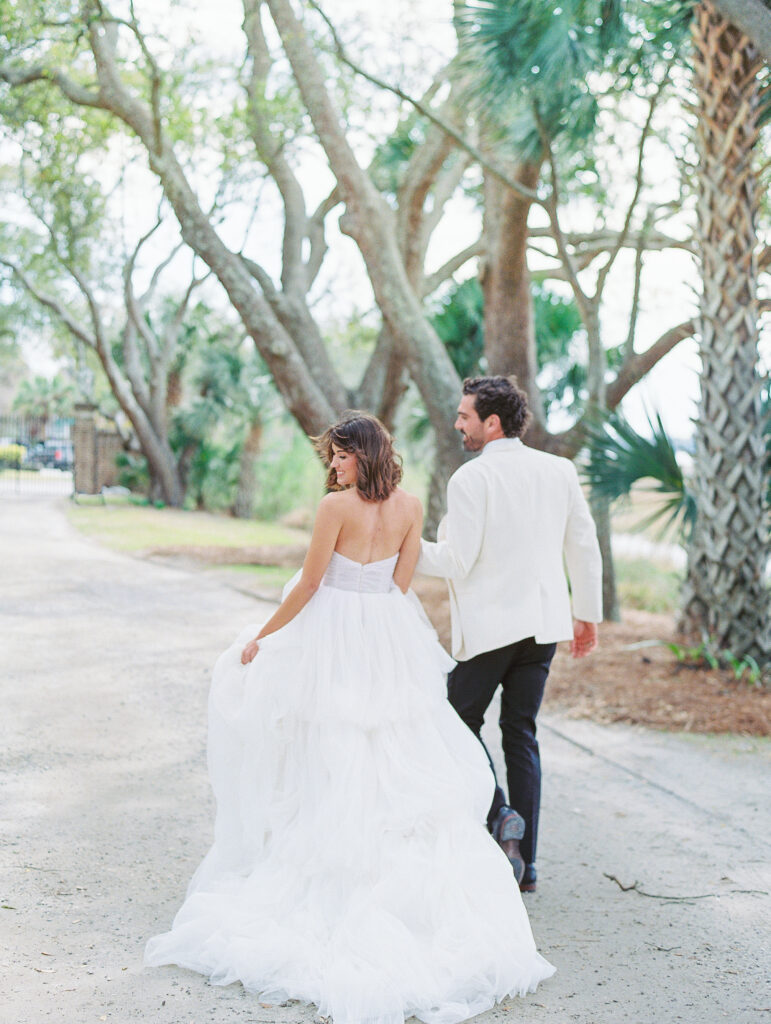 Lowdnes Grove Wedding by destination film wedding photographer Katie Trauffer Photography - bride and groom joyfully walk along palms