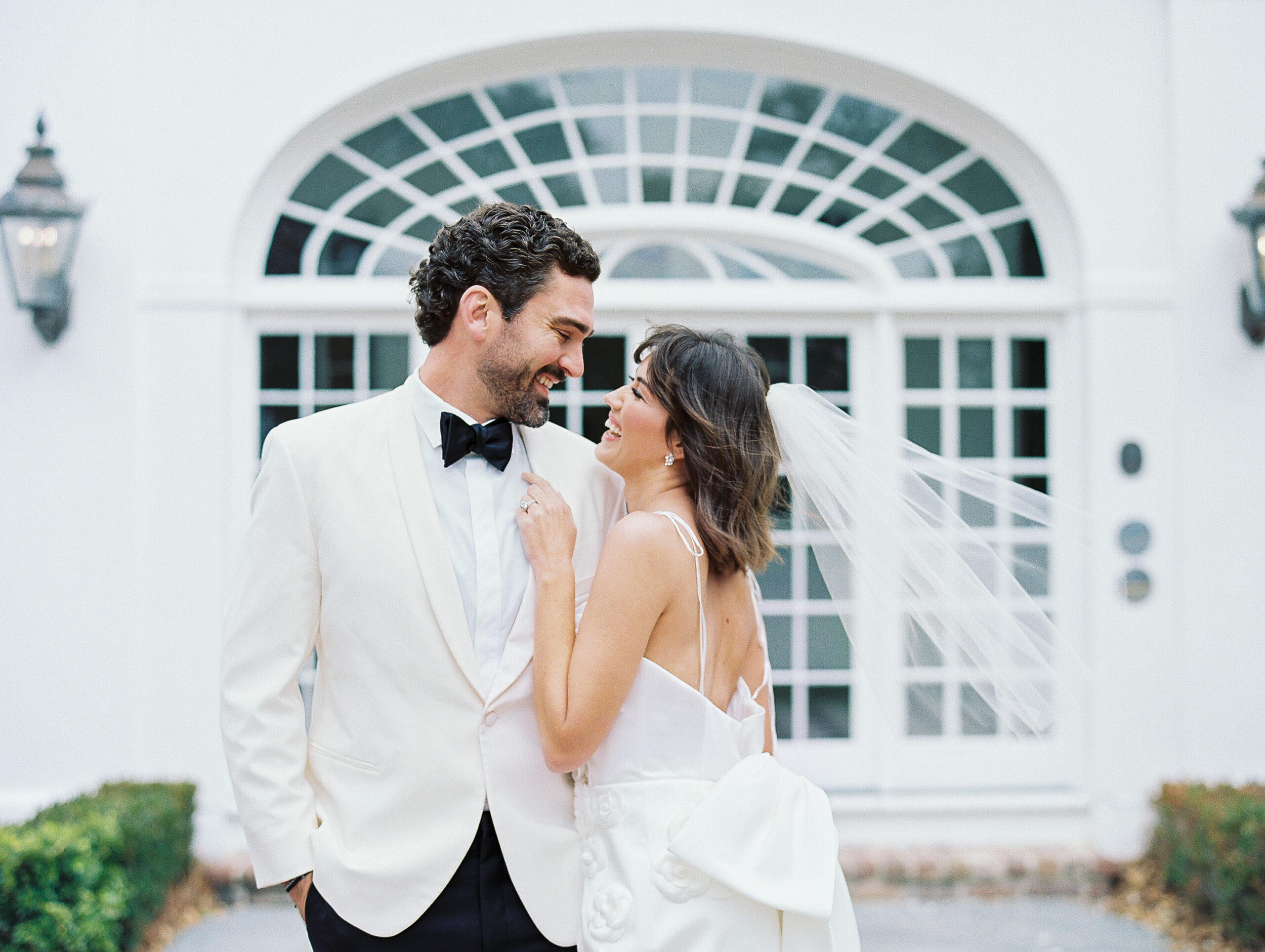 Lowdnes Grove Wedding by destination film wedding photographer Katie Trauffer Photography - bride and groom laugh and embrace in front of white building