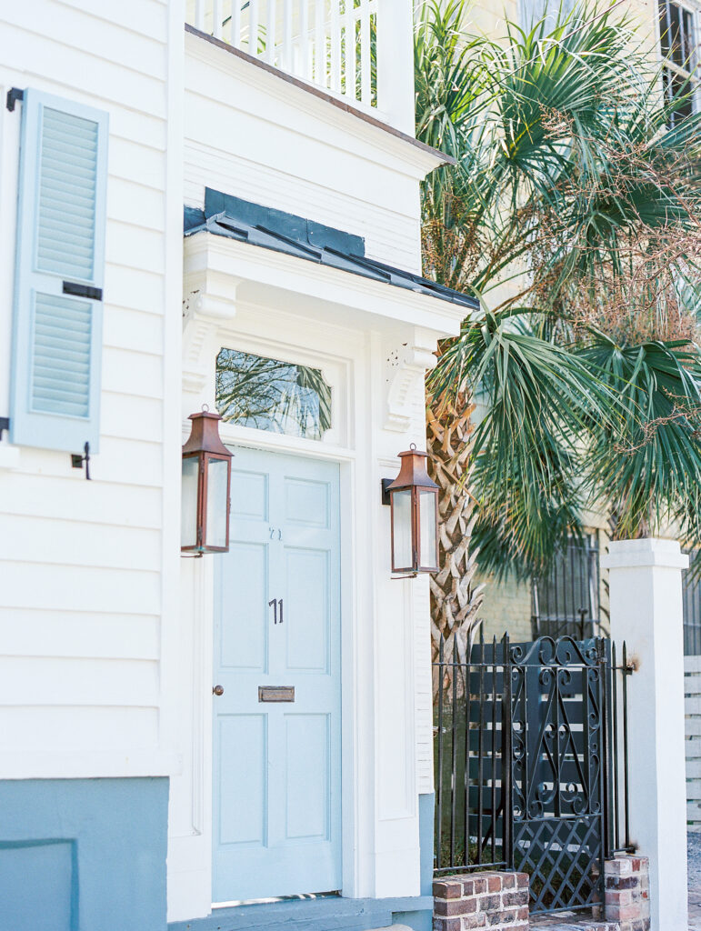 downtown charleston house with blue door and striking palm tree contrasted against white building