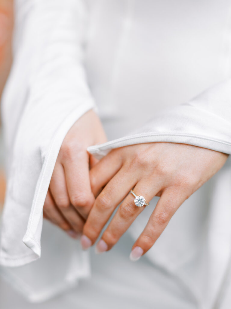 close up of bride's hands at engagement session showcasing beautiful round cut diamond ring
