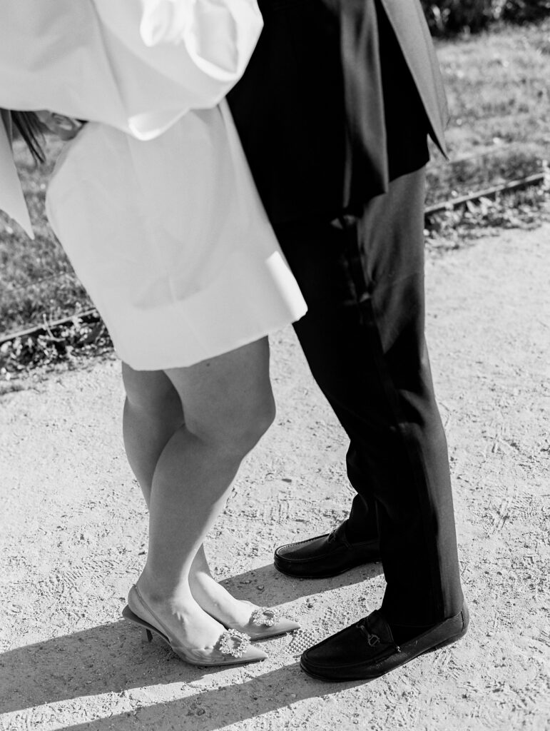bride and groom in stand together in black and white, focus on bride's Manolo Blahnik shoes