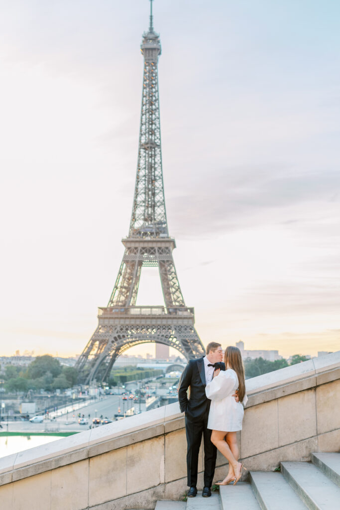 Couple kisses in front of Eiffel Tower at sunrise with golden sky