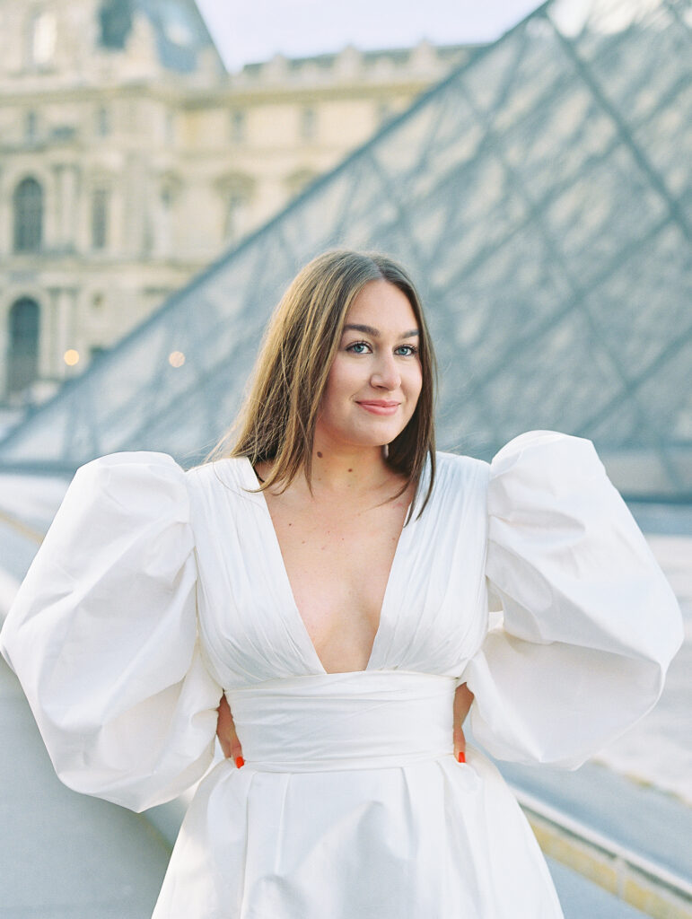 Louvre Elopment Bride smiles in chic fashion forward white dress with puff sleeves and deep V neck