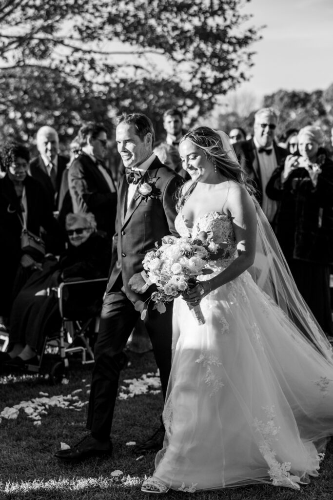black and white of bride and father walking down the aisle at garden wedding