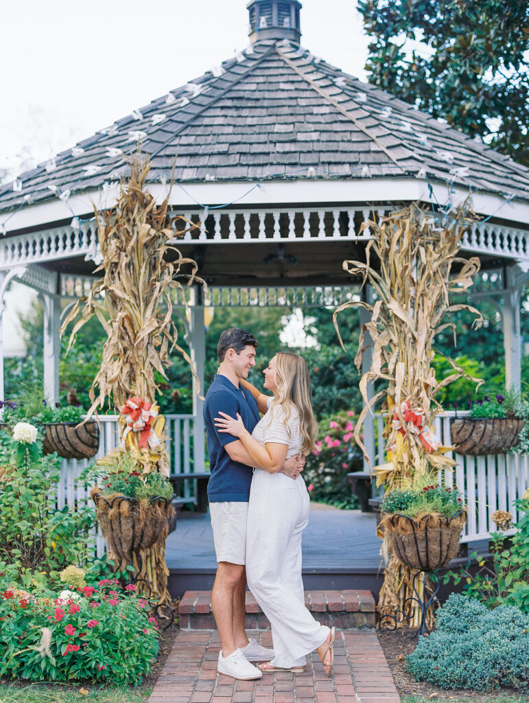 couple embraces in front of colorful gazebo