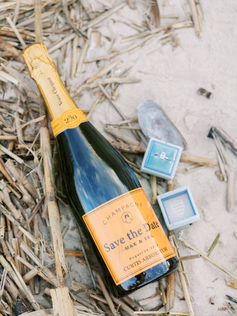 custom champagne bottle amid driftwood with blue engagement ring box