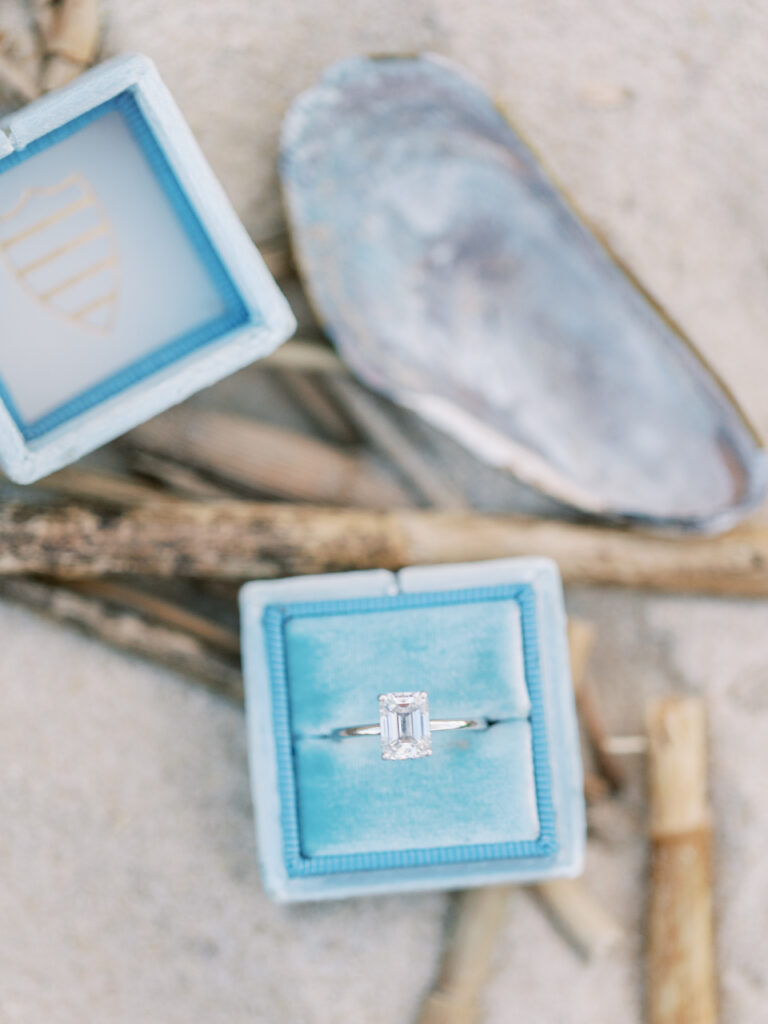 engagement ring in blue velvet box on beach