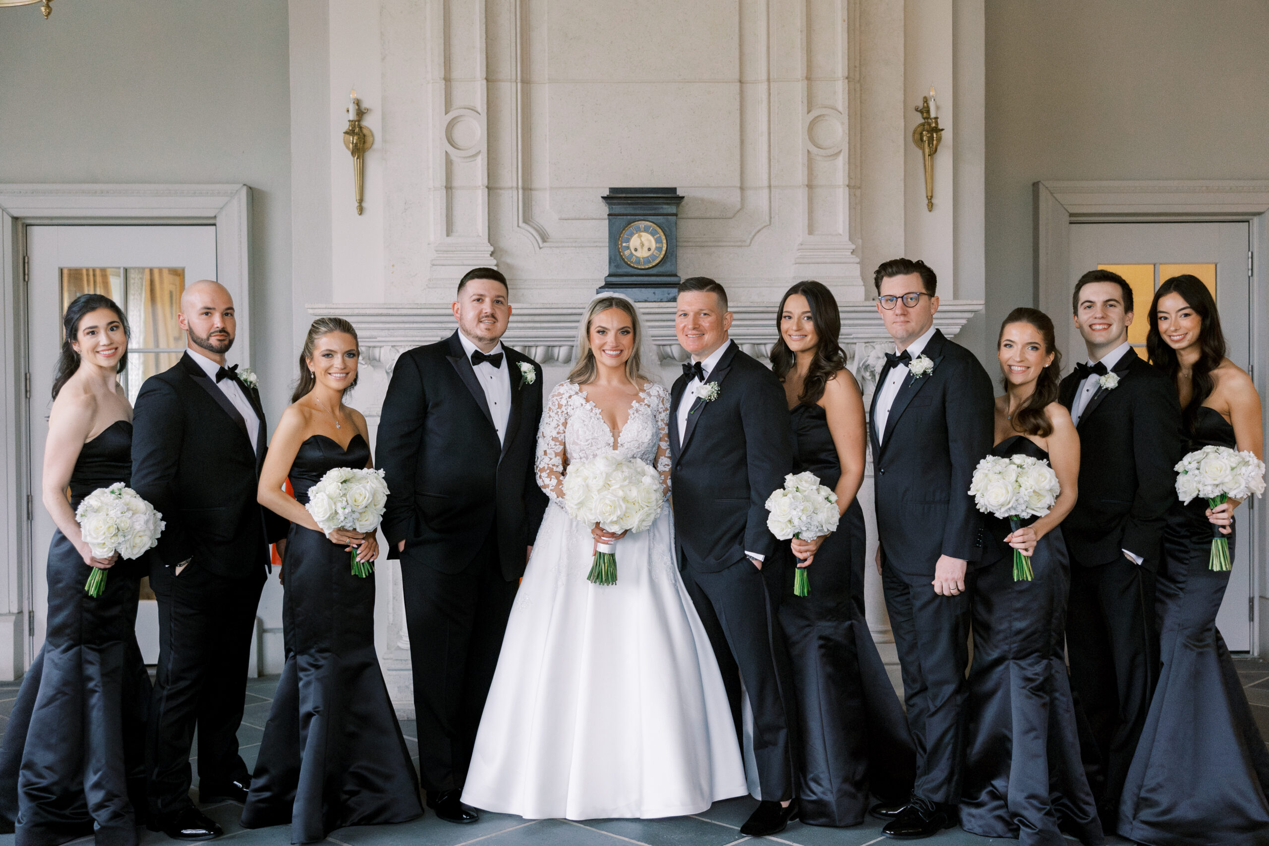bride and groom stand with bridesmaids and groomsmen dressed in all black