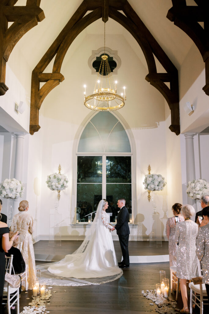 bride and groom stand in white chapel during ceremony