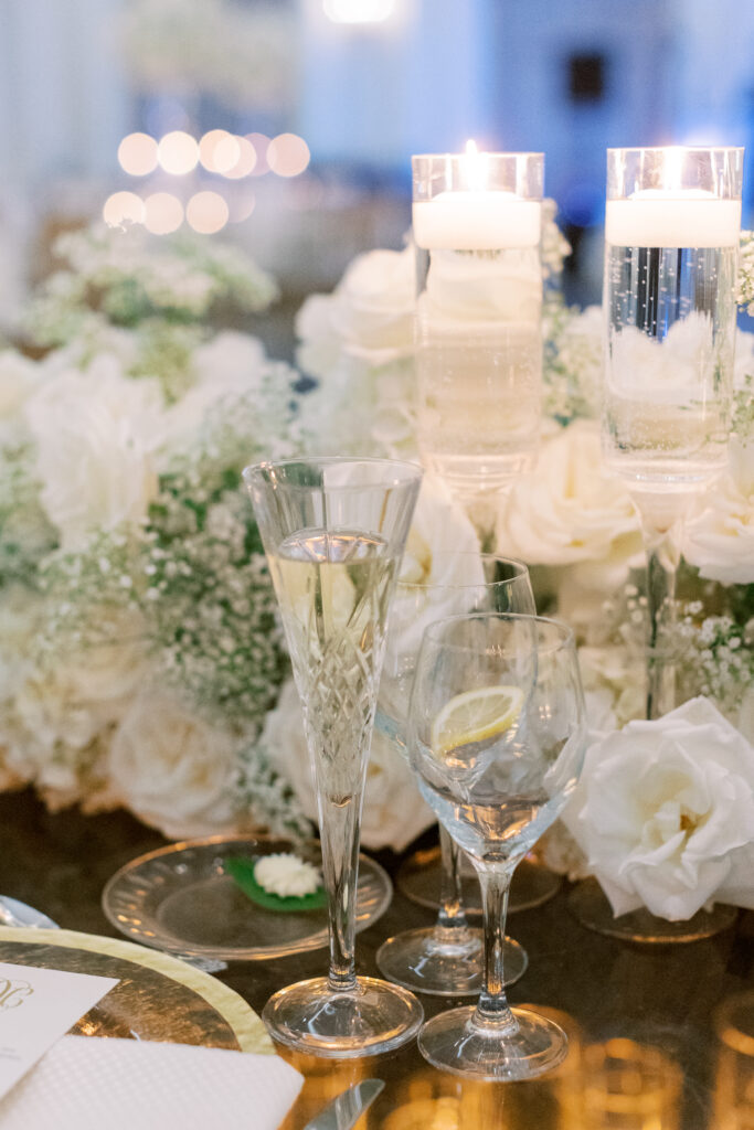 close up of champagne glass on flower covered sweetheart table
