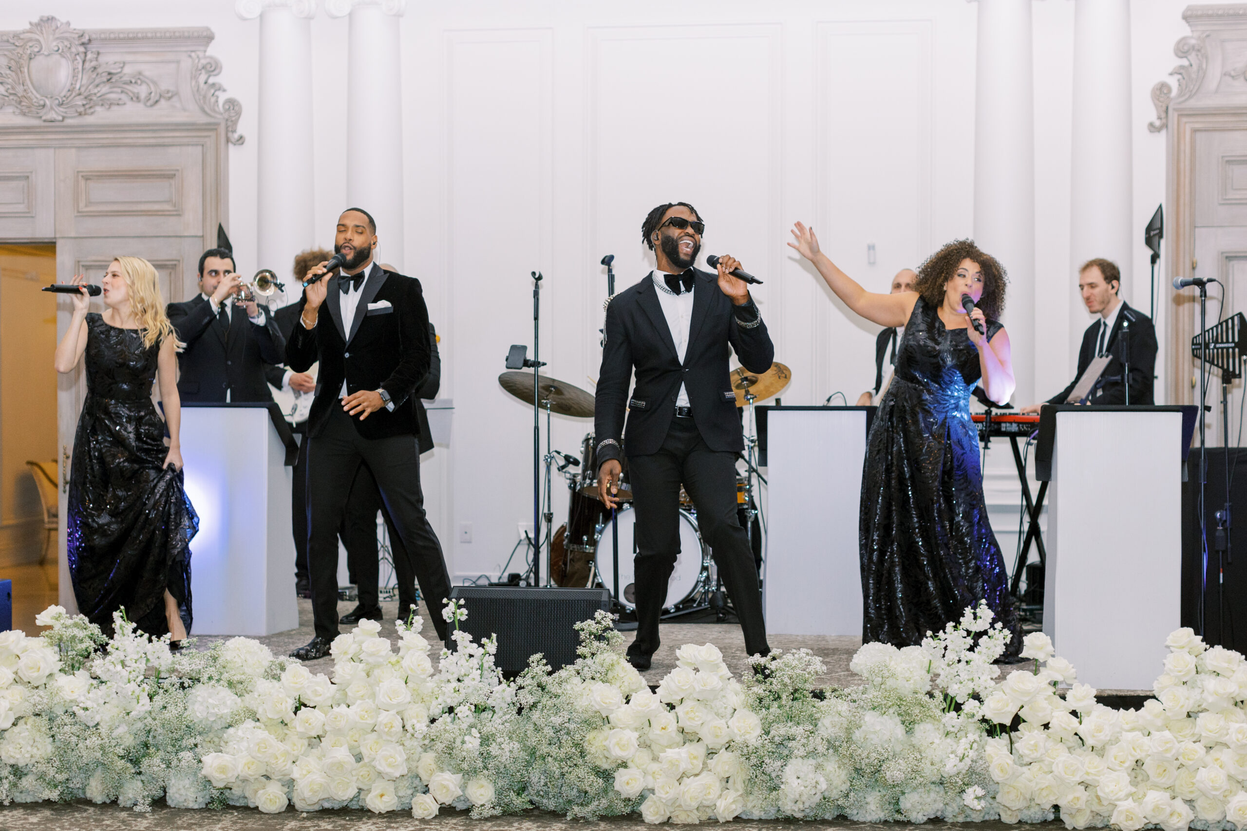 wedding band dressed in black performs energetically in front of flowers