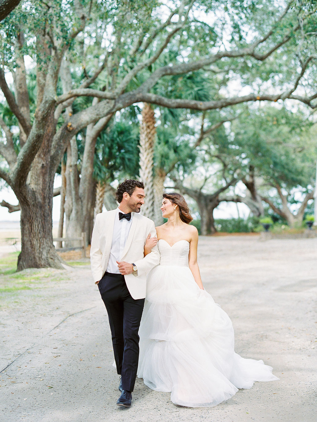 Intimate Lowndes Grove Wedding bride and groom walk hand in hand along oak trees