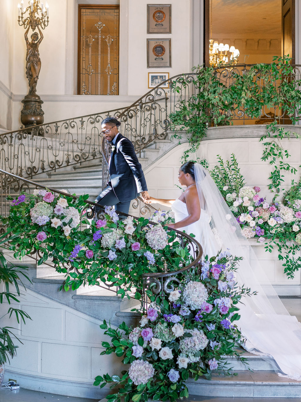 bride and groom walk up floral covered stairs Oheka Castle Wedding Photography